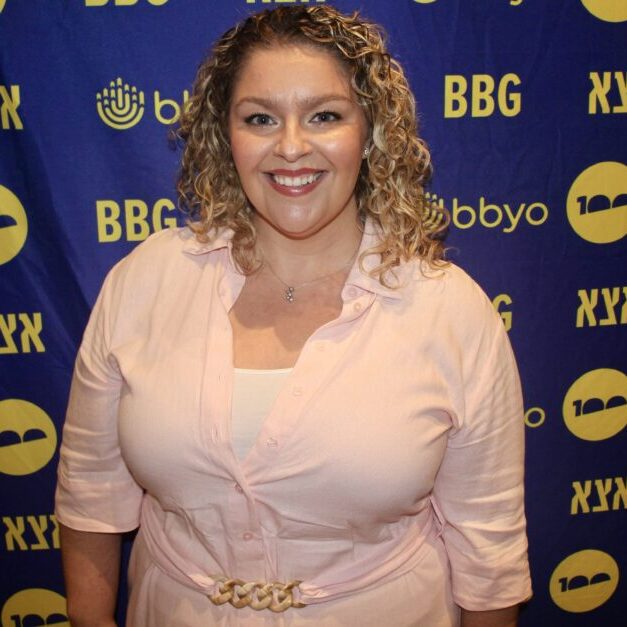 A diverse crowd of people celebrating at a concert, raising their hands and cheering.