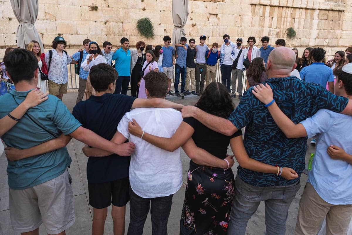 A diverse crowd of people celebrating at a concert, raising their hands and cheering.